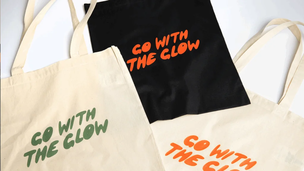 Tote bag featuring a vibrant design with the phrase "Go with the Glow" in bold, colorful lettering.