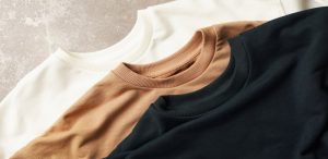 A white, brown, and black sweatshirt stacked on top of each other.