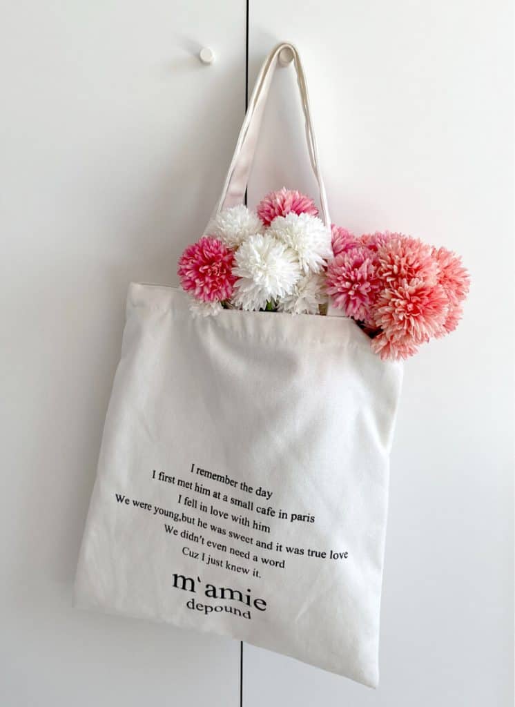An image of a custom tote bag with text design elements and a bouquet of flowers inside.