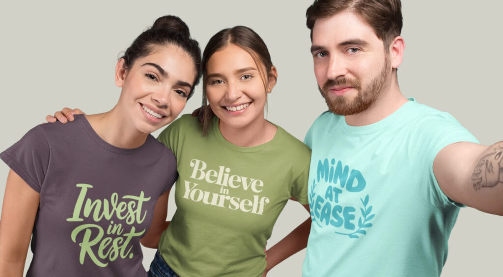 Three individuals wearing t-shirts that read "Believe in Yourself," smiling and standing together in a supportive pose.