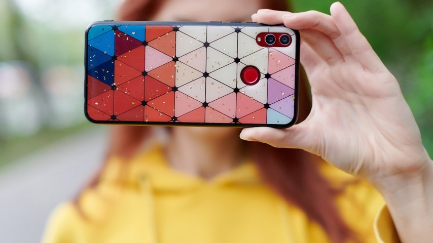 A person holds up a colorful, geometric phone case.