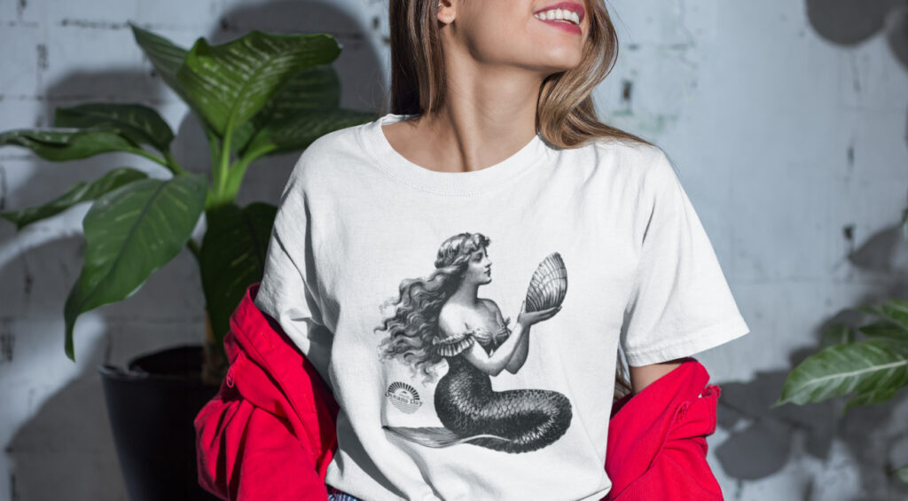 A colorful t-shirt featuring a whimsical mermaid design, surrounded by multiple mermaid illustrations.