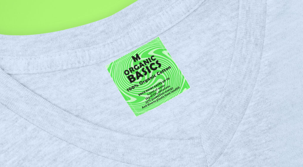 A light gray V-neck T-shirt with a vibrant green tag labeled "Organic Basics" and "100% Organic Cotton" on a bright green background.
