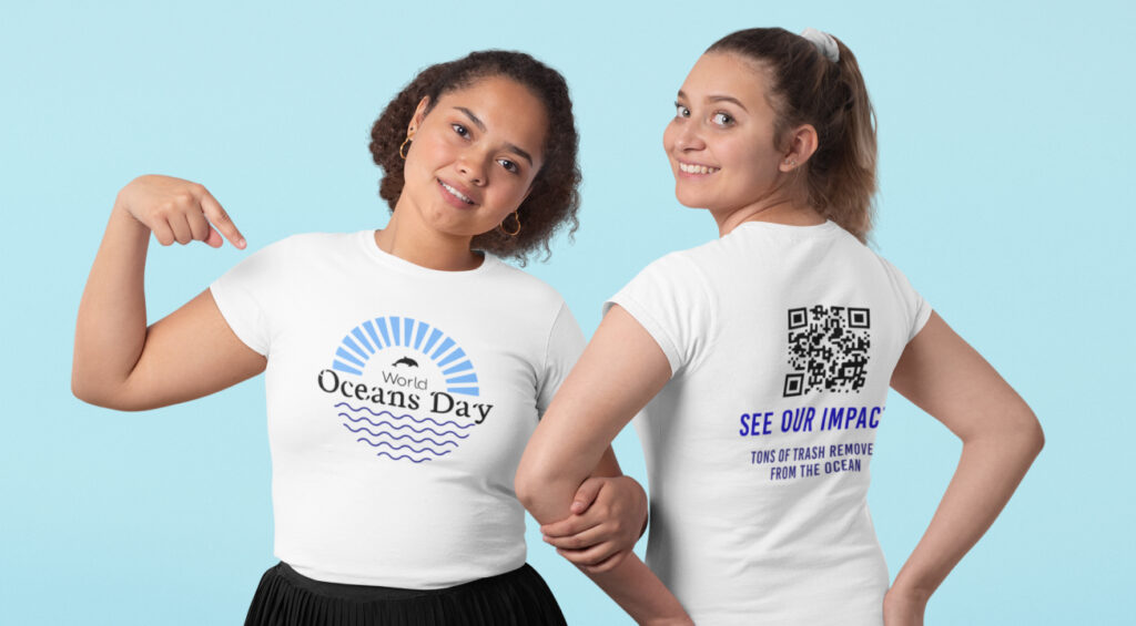 Two women wearing matching t-shirts that read "Ocean Day," smiling and enjoying a sunny outdoor setting.