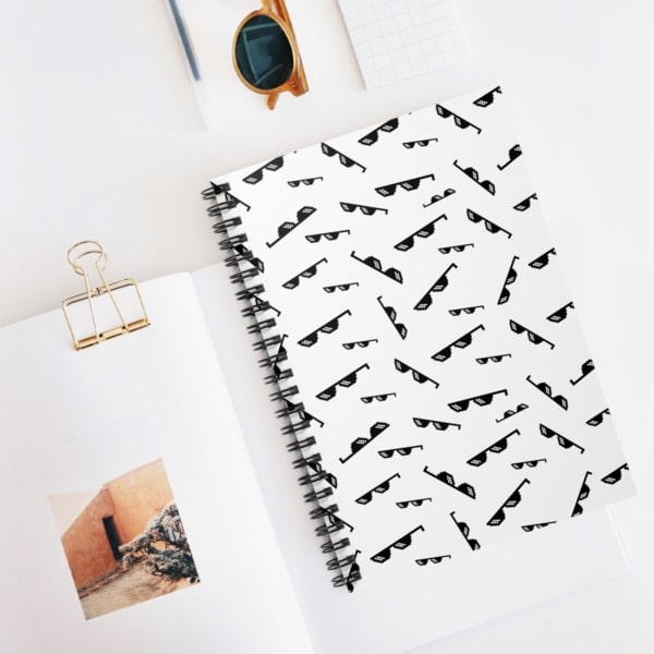 A white notebook with a repeat pattern of small pixelated sunglasses.
