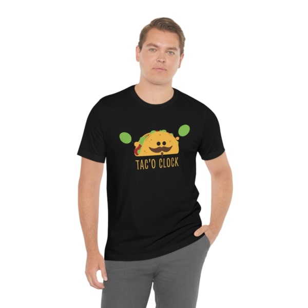 A black t-shirt with a design of a cartoon taco with a mustache and the text “Tac'o Clock.”