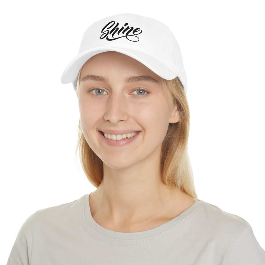 A woman wearing a white cap with the word "Shine" on it.