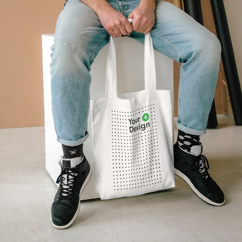 A mockup of a person holding a cotton tote bag in his arms.