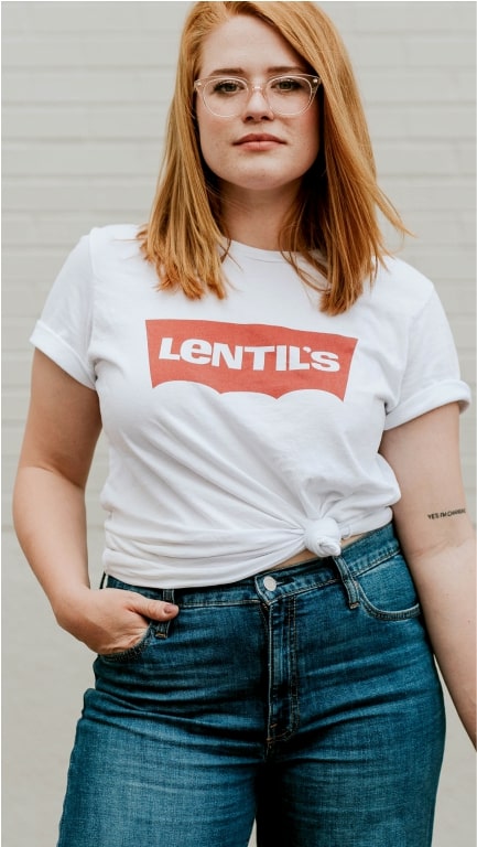 A young woman posing in jeans and a white t-shirt with the word "lentil's" on it.