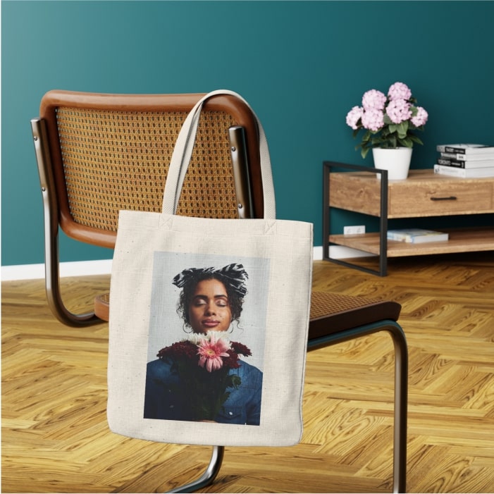 A mockup with a custom tote bag with an abstract picture hanging on a chair.