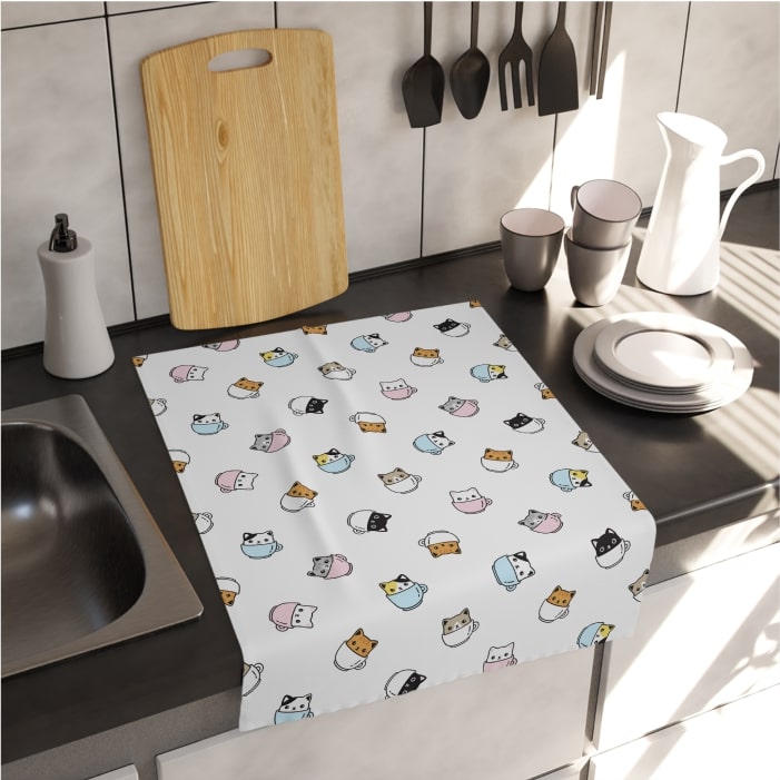 White tea towel with a pattern of cute cartoon kittens in teacups.