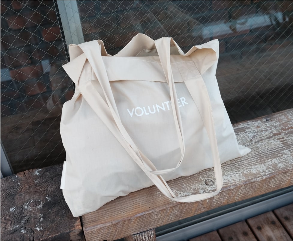A picture of a personalized tote with the word “Volunteer” lying on a bench.