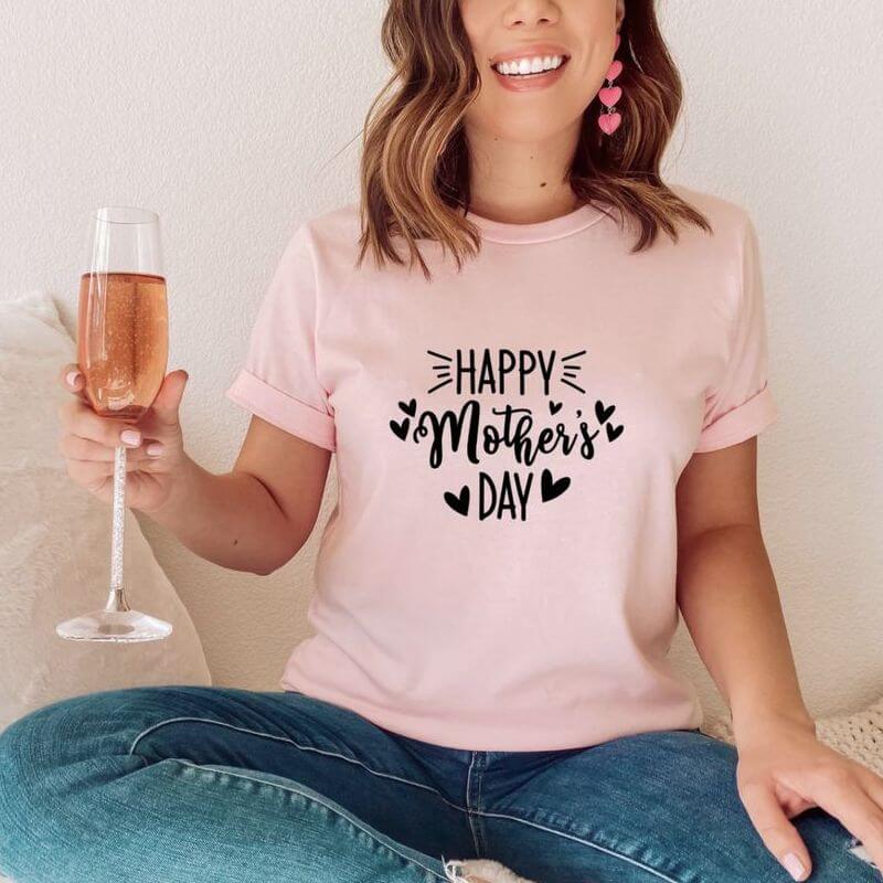 A woman enjoying champagne in a pink t-shirt that says "Happy Mother's Day"
