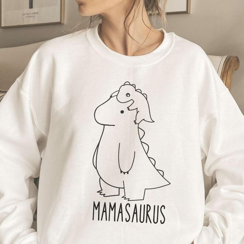 A cute sweatshirt with baby dinosaur climbing on mama dinosaur that says "Mamasaurus"