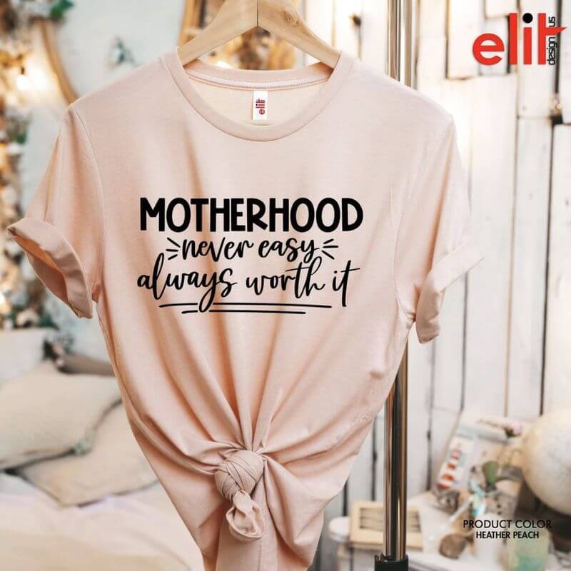 A hanging pink t-shirt that says "Motherhood: never easy, always worth it"