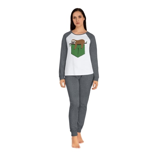 Woman wearing a white and grey pyjama set with an image of a sleeping sloth on the front of the shirt.