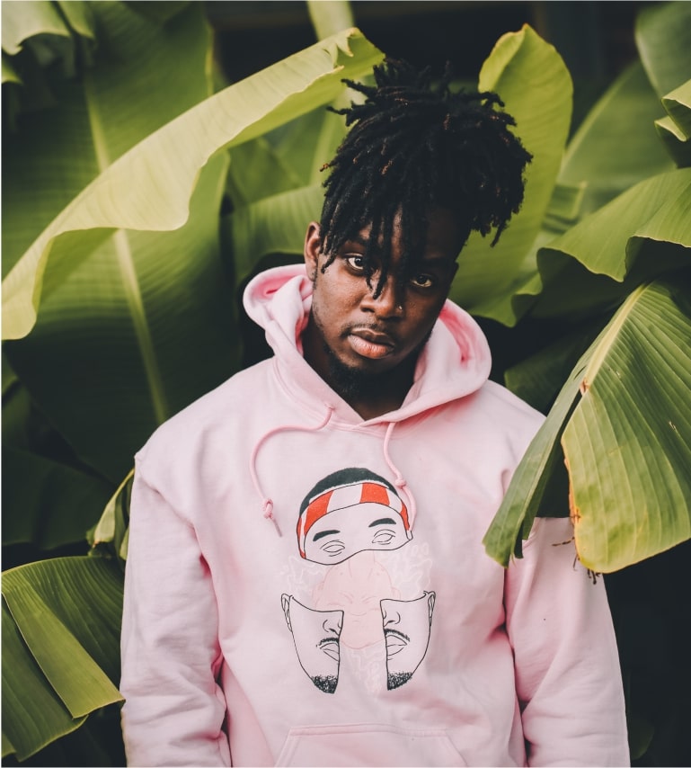 A guy posing with an abstract-design hoodie in a jungle setting for the eco-friendly segment