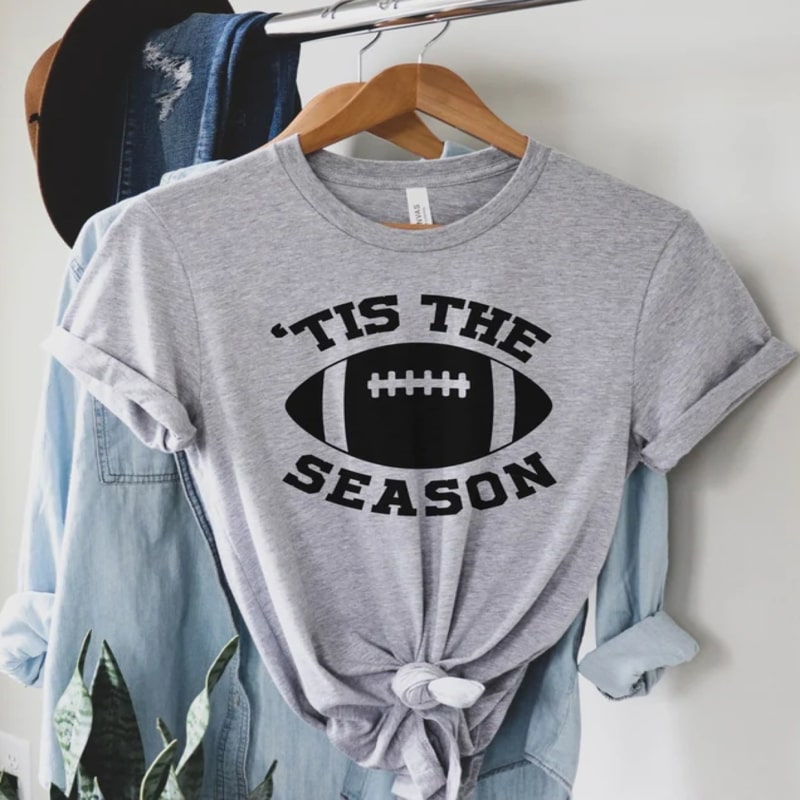 Grey shirt with an image of a football and the text "'Tis the Season" wrapped around it.