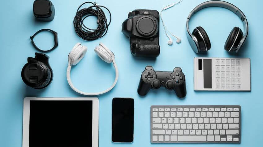 A set of electronics that includes headphones, camera, phone, tablet, keyboard, and game controller.