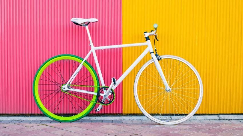 A white bicycle on a bright pink and yellow background.