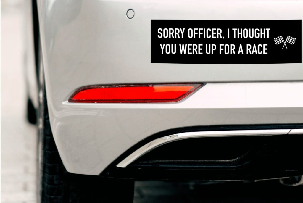 Custom bumper sticker on the rear of a car reading "Sorry officer, I though you were up for a race".