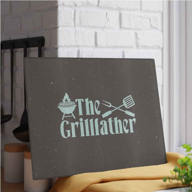 A black cutting board with a custom design that says "The Grillfather"