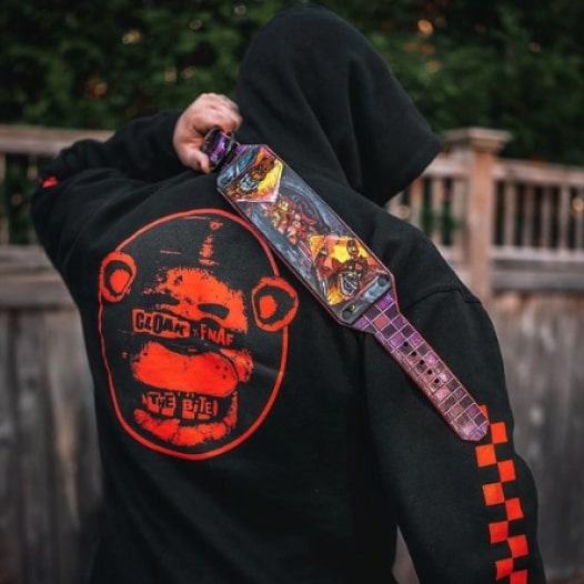 A man wearing a black hoodie with the design of a bear and the text “Cloak x FNAF: The Bite” printed on the back.
