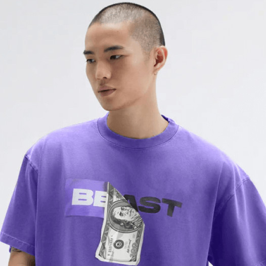 A man wearing a purple tee with the word “Beast” and a dollar bill design on the front.