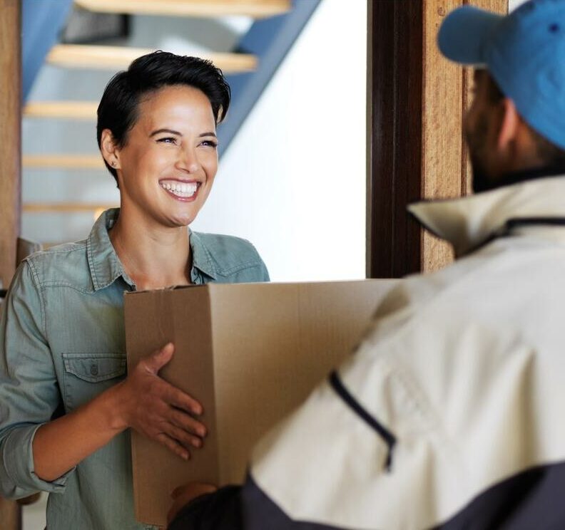 Woman happily receiving a large box delivery from a courier.