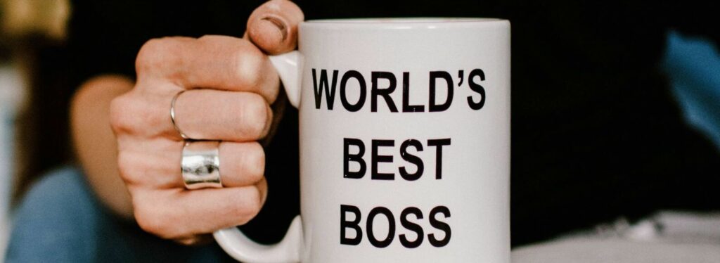 A hand holds a mug that says Worlds Best Boss