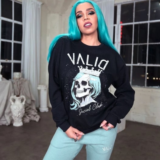 A woman wearing a black hoodie with a skeleton design and the text “Valid” printed above it.