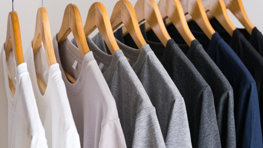 A rack of white, light gray, dark gray, blue, and black t-shirts.