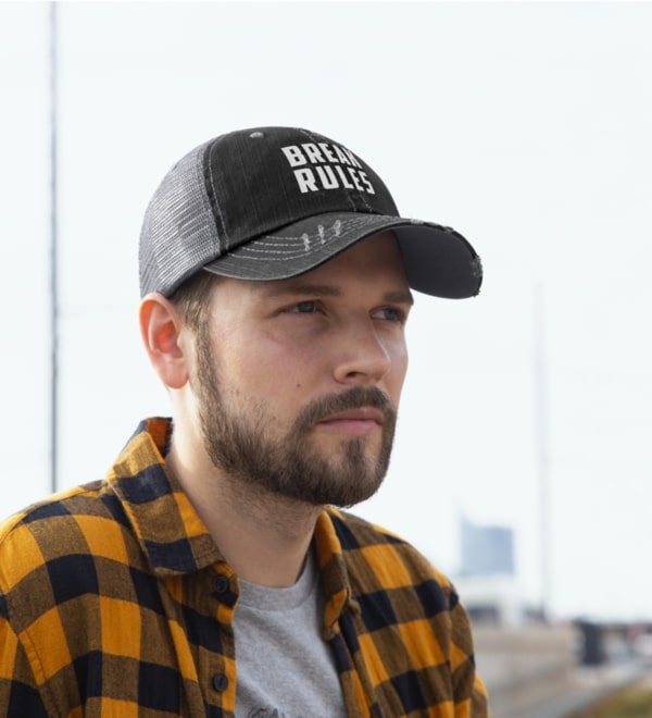 A man wearing a black custom trucket hat with text on it.