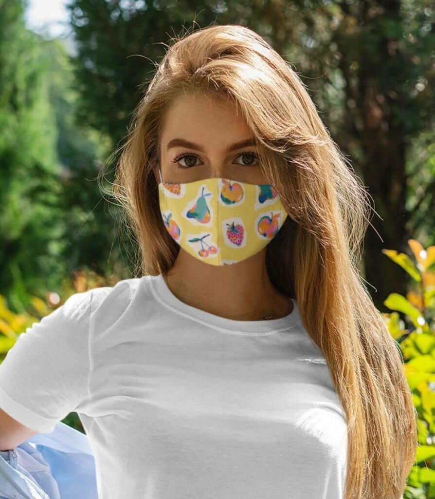 A woman posing outdoors in white t-shirt and custom face mask with fruity pattern