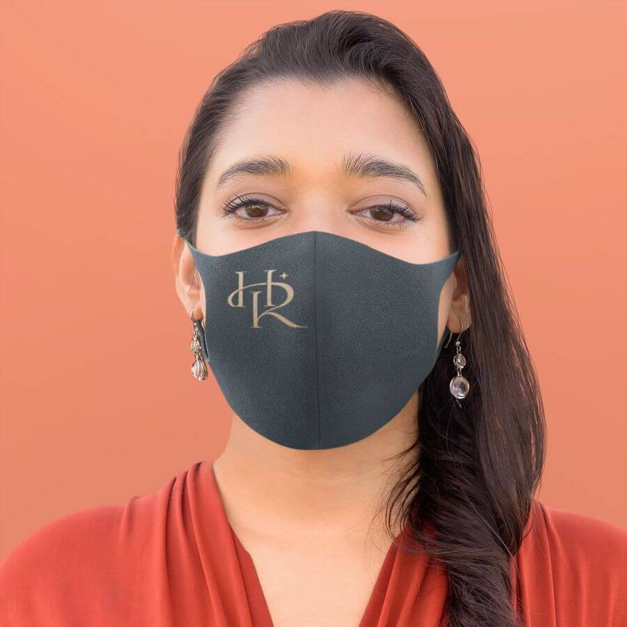 A woman posing in a black face mask that has a logo on it