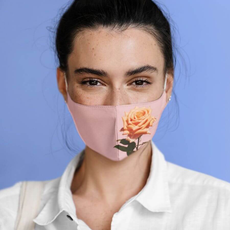 A woman posing with a pink face mask that has a rose on the left side