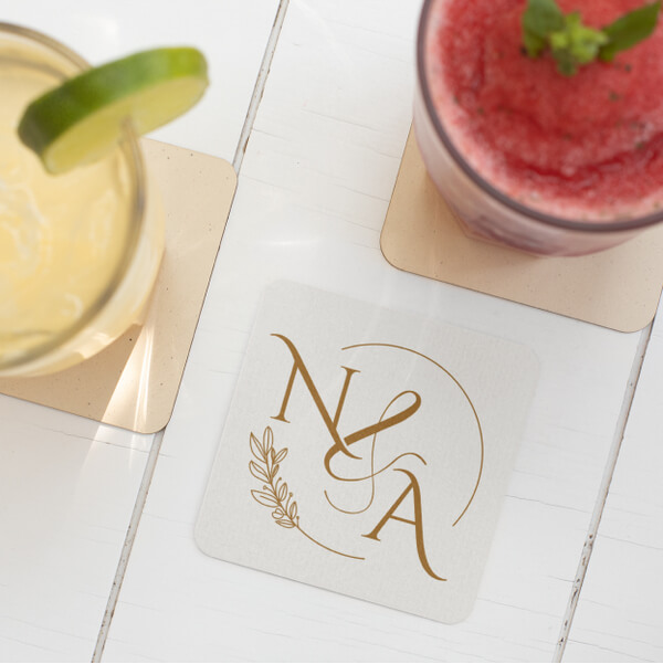 Square monogrammed coaster with the initials “N & A” surrounded by cocktail glasses.