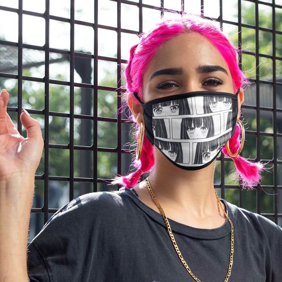 A woman with pink hair posing at a fence with a face mask that has a comic pattern