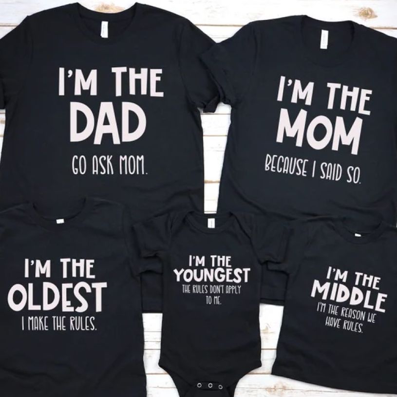 Four black t-shirts and a baby onesie, each of them displaying family-related writings, e.g., “I'm the Dad. Go ask mom,” “I'm the mom. Because I said so.”