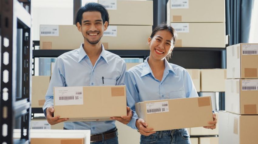 Smiling man and a woman holding boxes of dropshipping orders.