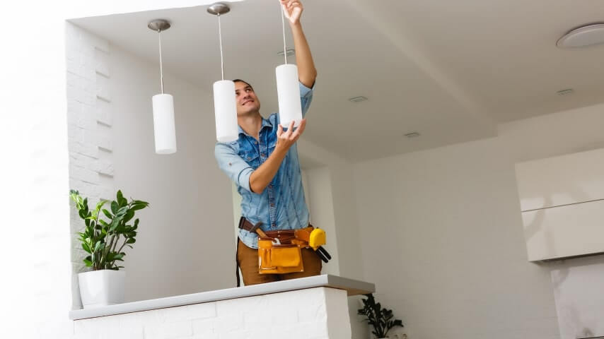 Home maintenance professional attaching lamp fixtures to the ceiling.