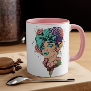 White mug with a pink inner accent and an illustration of a stylized woman with colorful flowers in her hair.