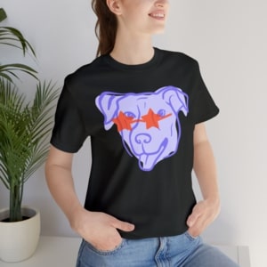 Woman wearing a black t-shirt with a design of a purple cartoon dog with star-shaped sunglasses.