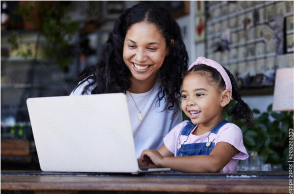 A woman and her daughter watching something on a laptop and smiling