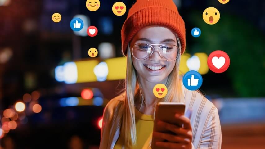 Young woman with glasses smiling at her phone, surrounded by social media reaction icons.