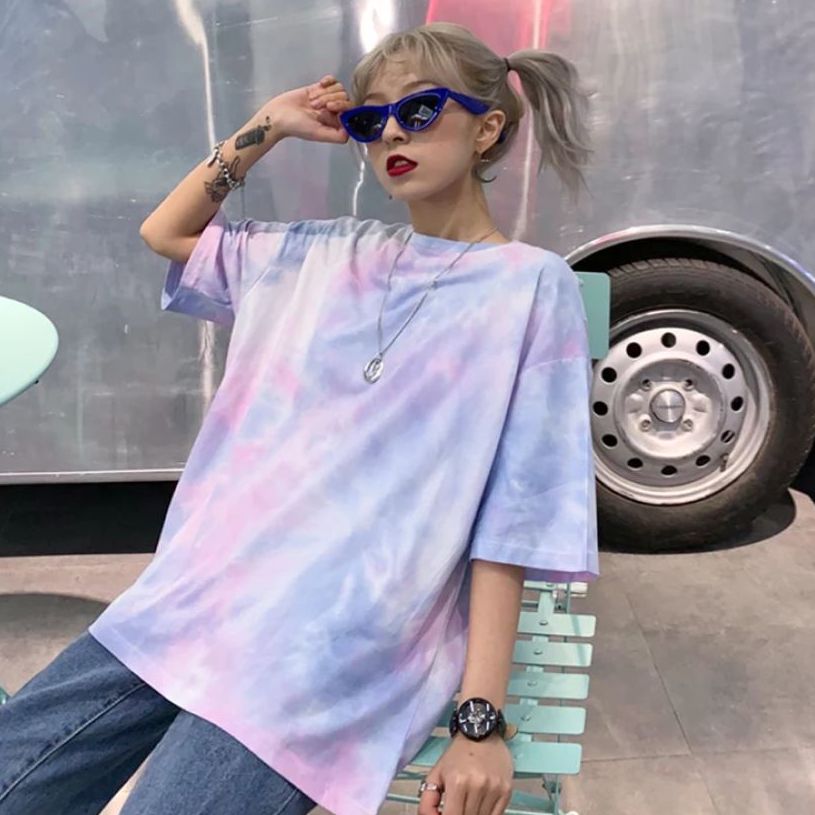 A stylish girl in sunglasses wearing an oversized tie-dye t-shirt in blue, purple, and pink tones.