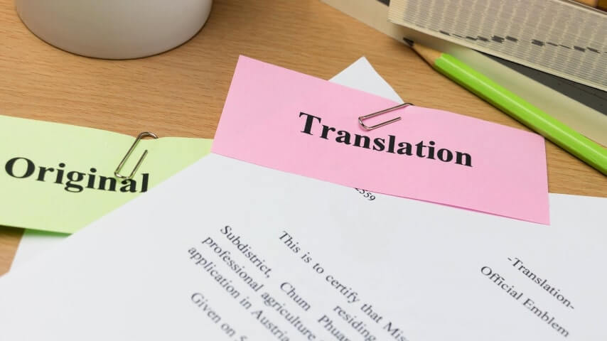 A stack of papers on a desk labelled “Original” and “Translation.”