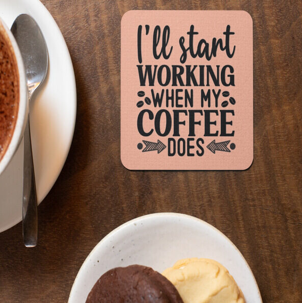 Beige square coaster with the text “I'll start working when my coffee does” with design elements of coffee beans and arrows.