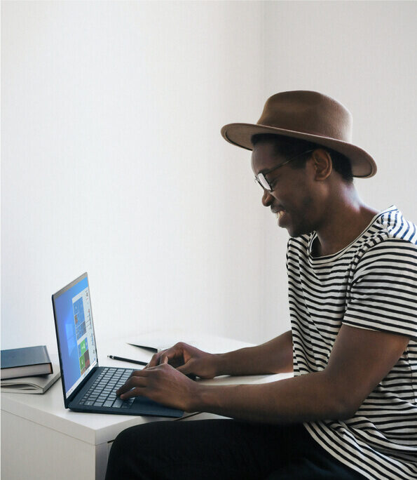 A young man sitting at a desk, working with a laptop