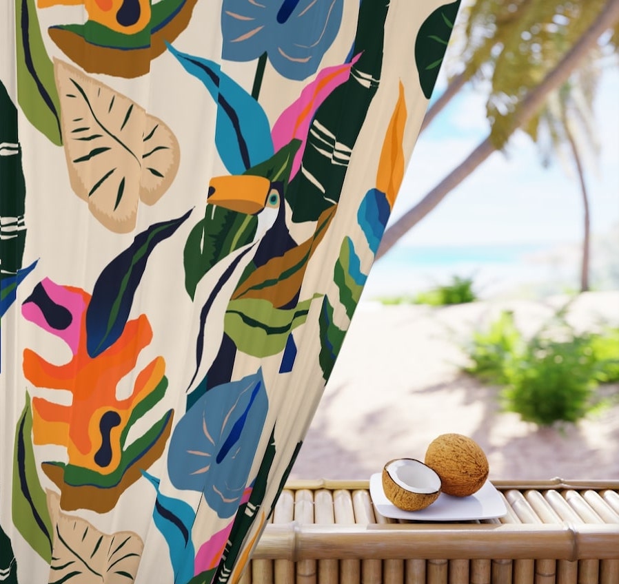 Custom curtain close-up with a printed design of tropical leaf and bird patterns framing a warm beach resort.